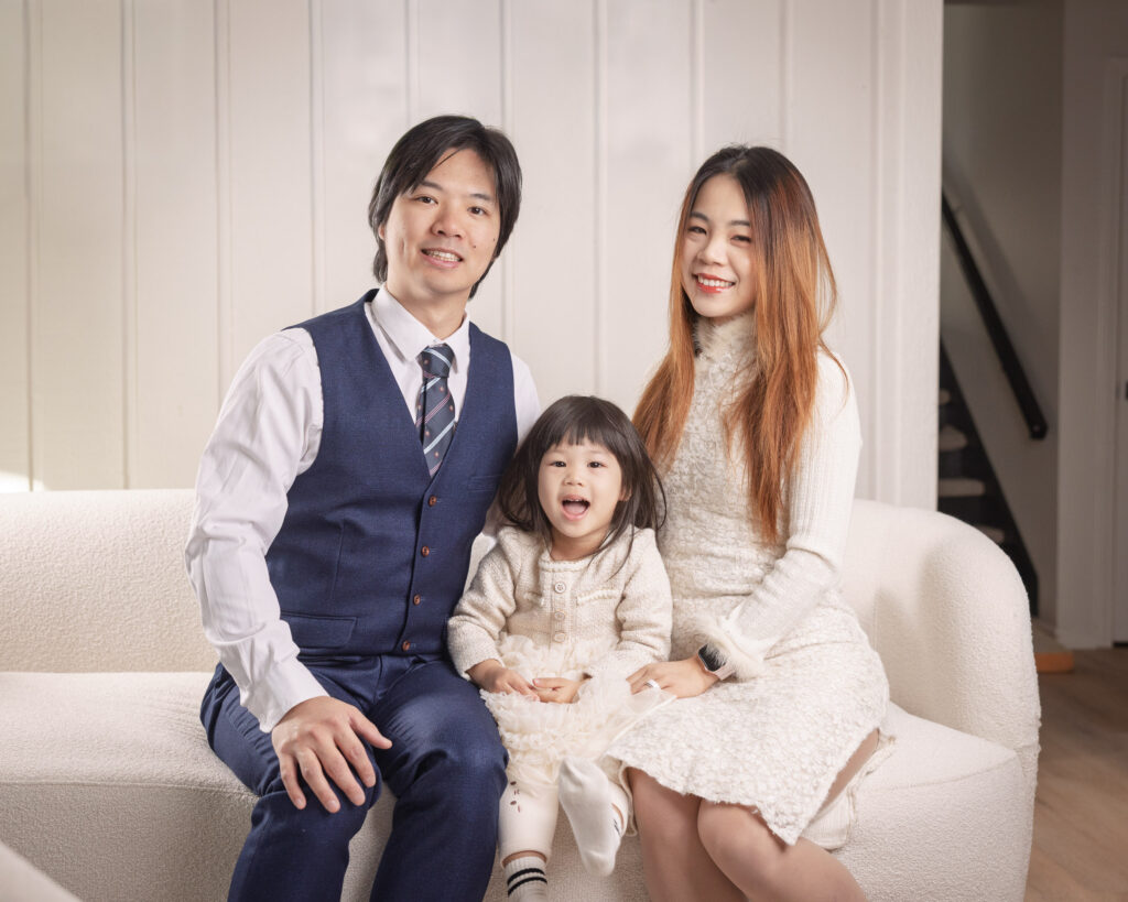 Parents sitting on a sofa with their toddler during an in-home family anniversary photography session