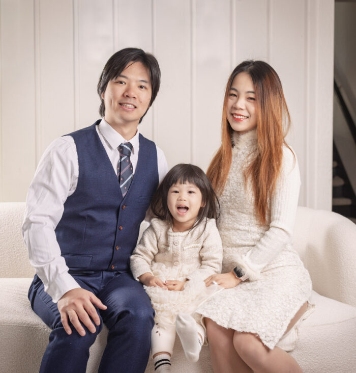 Parents sitting on a sofa with their toddler during an in-home family anniversary photography session