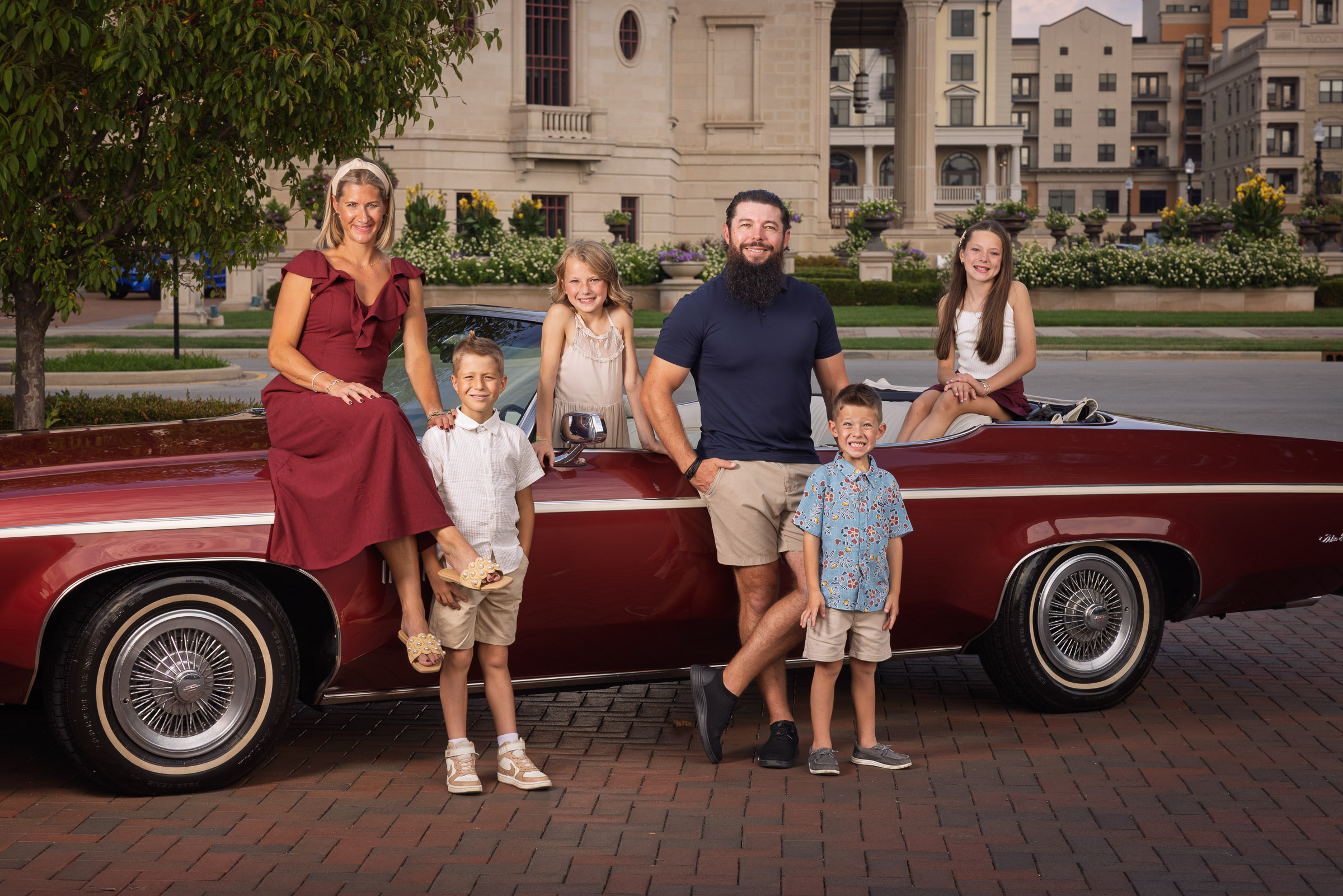 Family of six with a vintage red convertible on the brick streets of Carmel's City Center