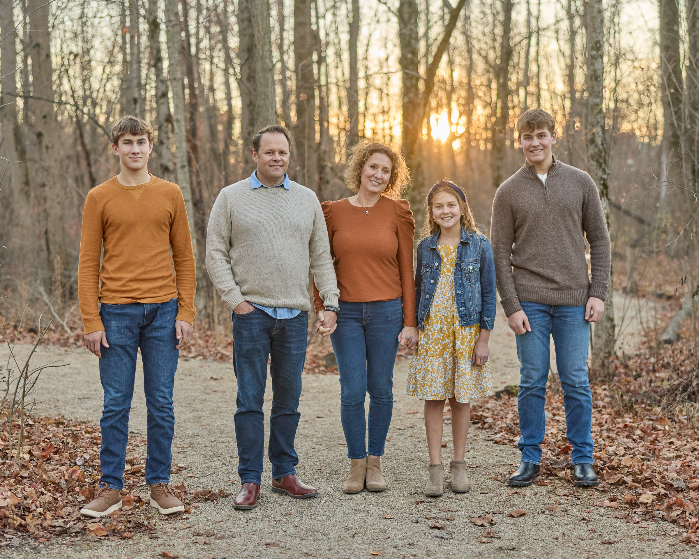 Family of five standing on a wooded path at sunset in Carmel, Indiana
