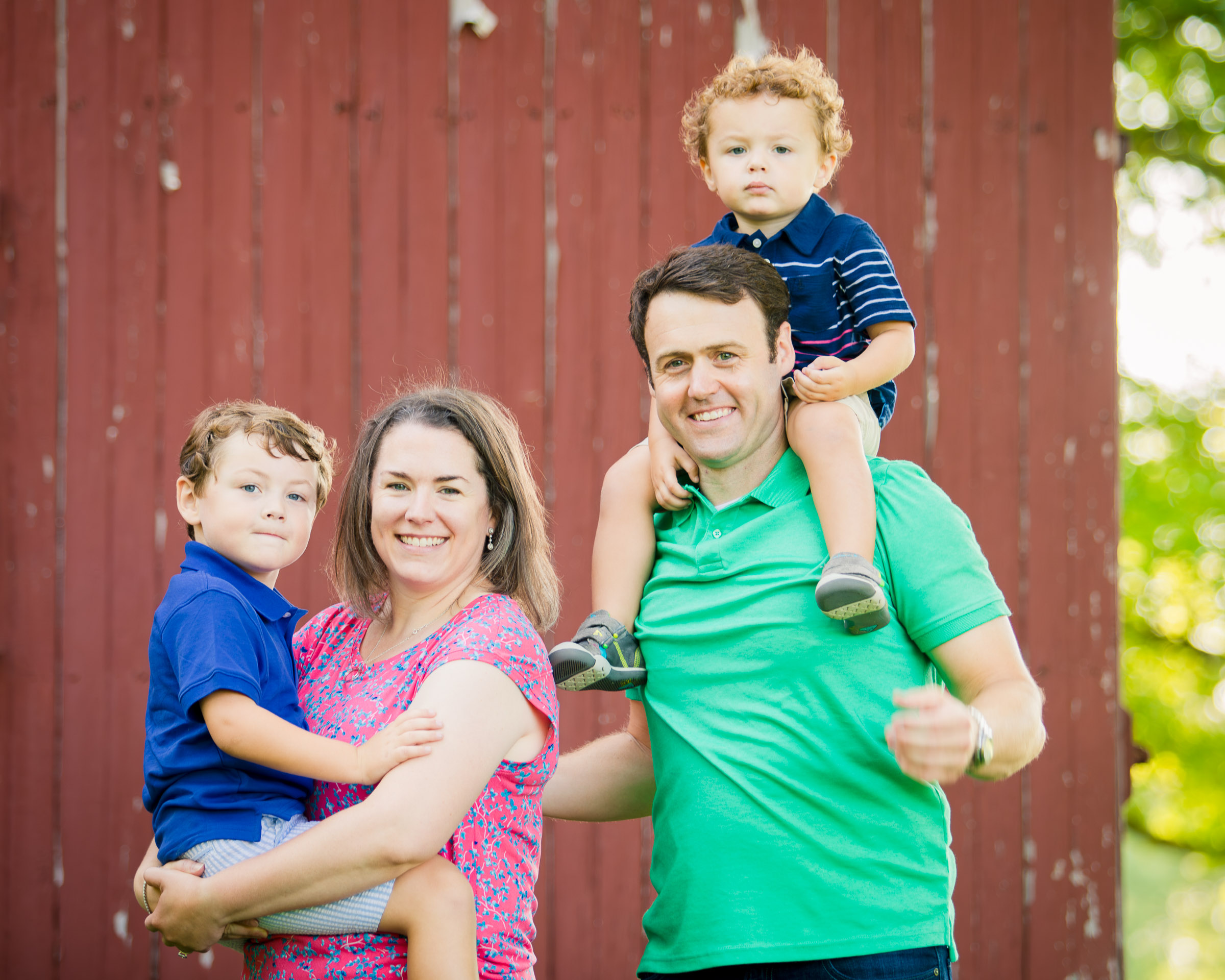 Parents with two young boys in front of the red barn at Coxhall Gardens in Carmel, Indiana