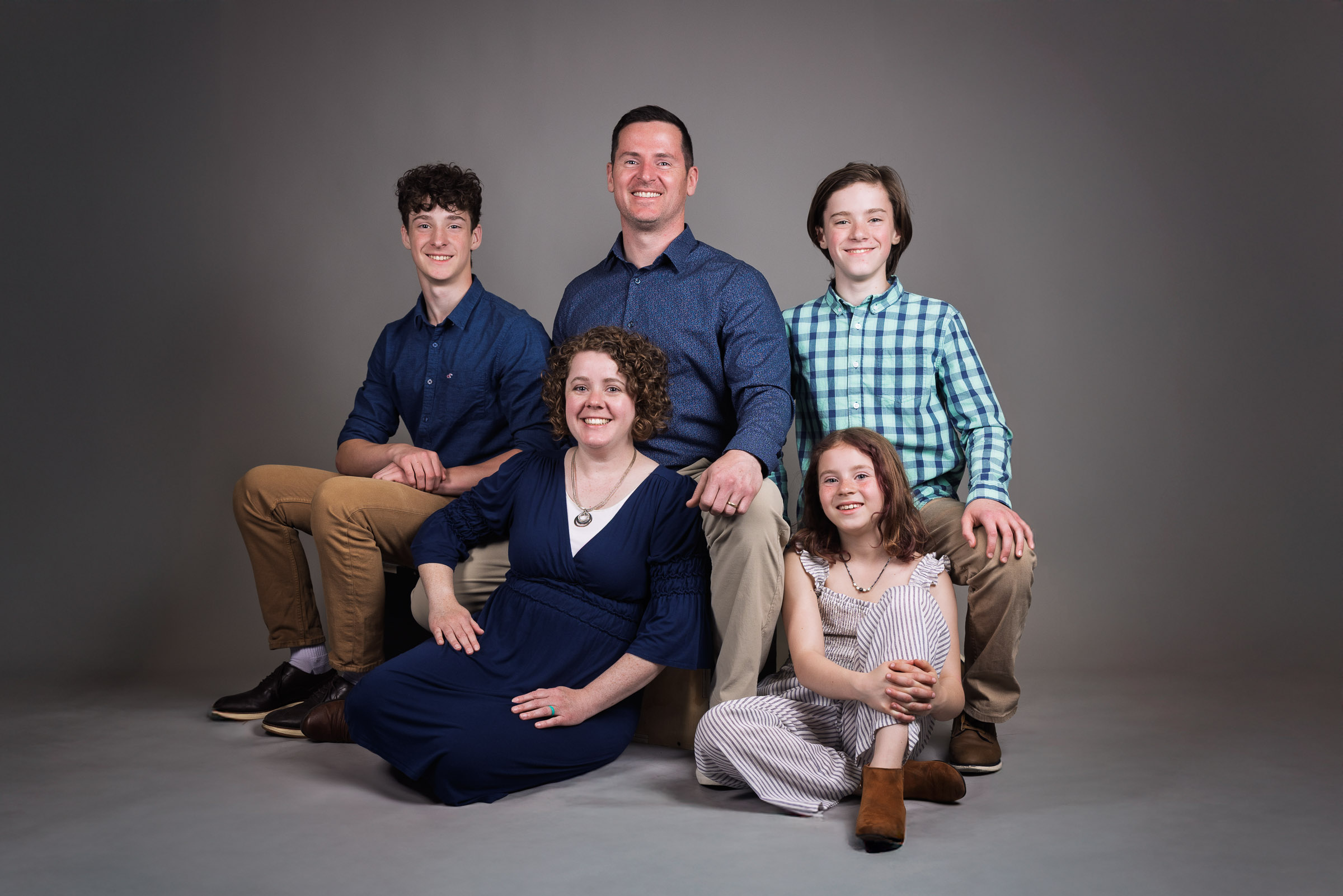 Family of six seated together on a grey studio backdrop
