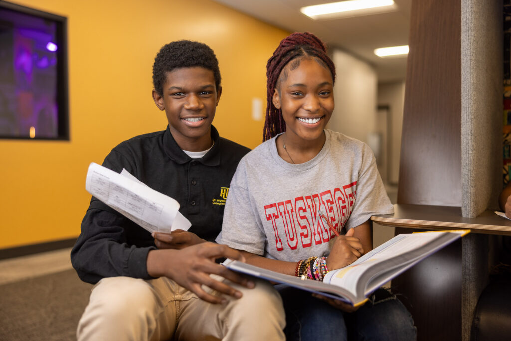 Two older charter school students smiling while reviewing schoolwork together