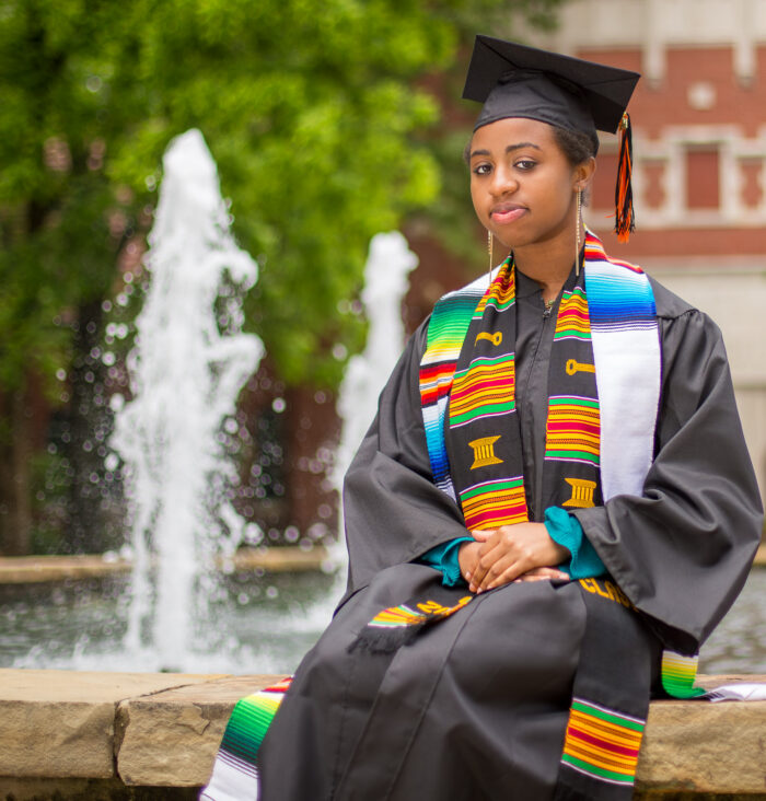 Graduation senior portrait in cap and gown by a fountain in Carmel, Indiana