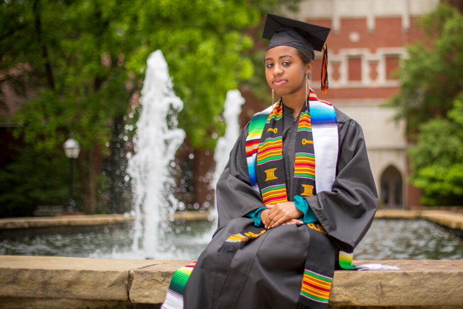 Graduation senior portrait in cap and gown by a fountain in Carmel, Indiana