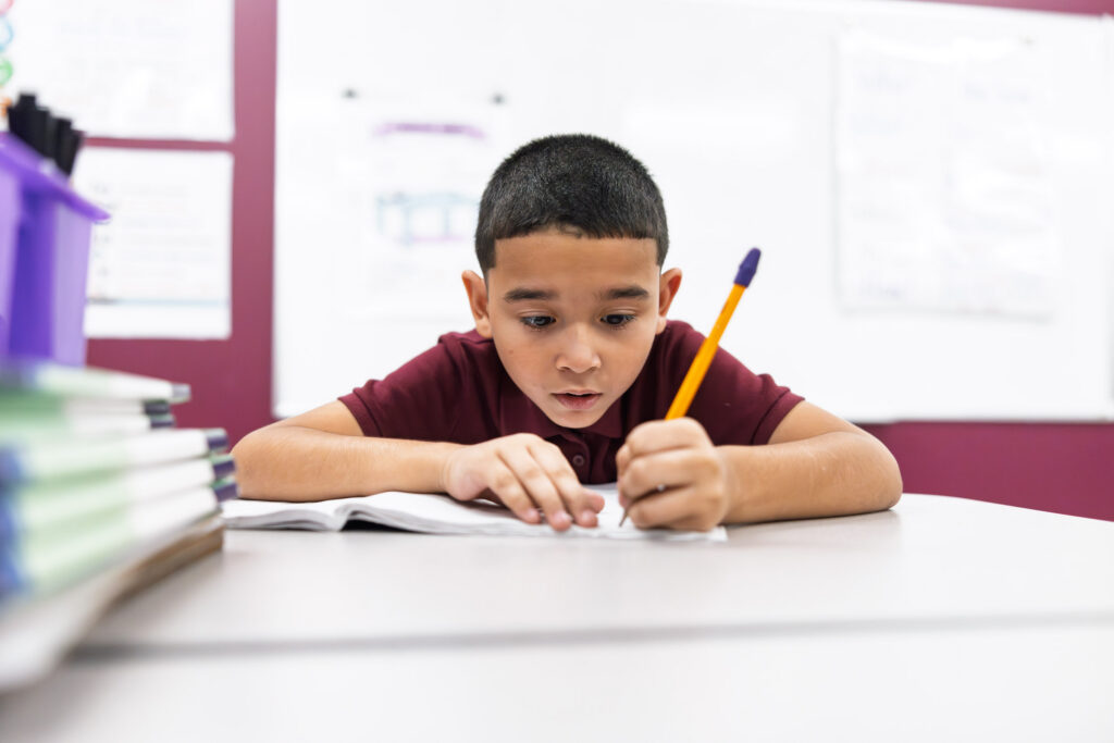 Elementary student writing at a desk in a charter school classroom