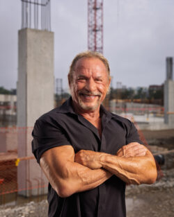 Portrait of a smiling man with folded arms on a construction site at dusk