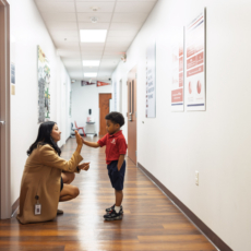 Teacher connecting with student in hallway at Houston Classical Charter School