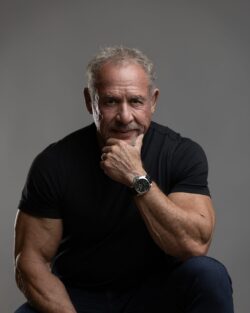 Executive-style headshot of a man seated with hand to chin, gray backdrop, Carmel, Indiana portrait studio